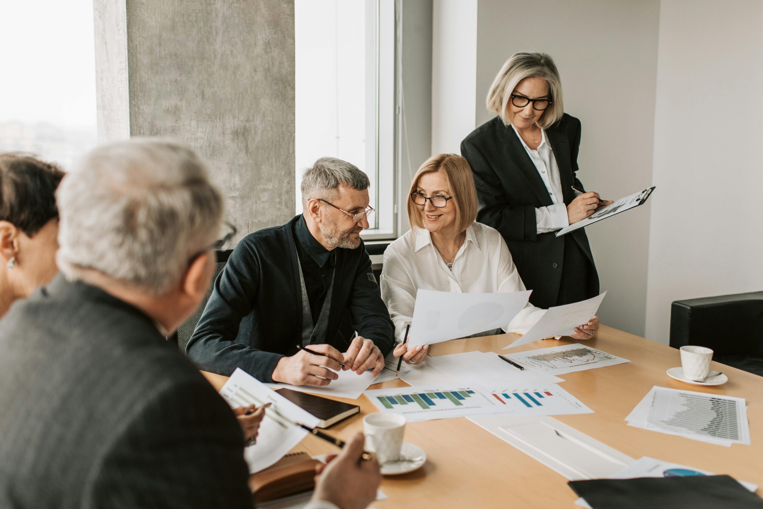 Group of people discussing sales growth while holding documents